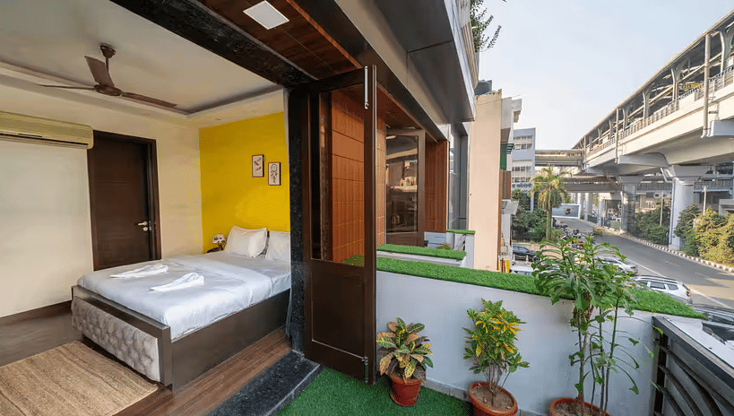 A hotel room with a balcony overlooking the metro line and urban surroundings - Lime Boutique Bed & Breakfast | Nehru Place Metro